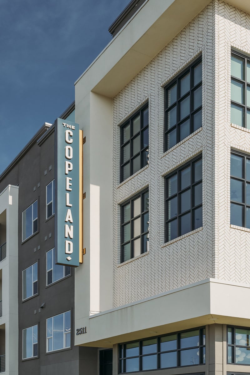A modern apartment building with a sign that reads The Copeland and large windows.