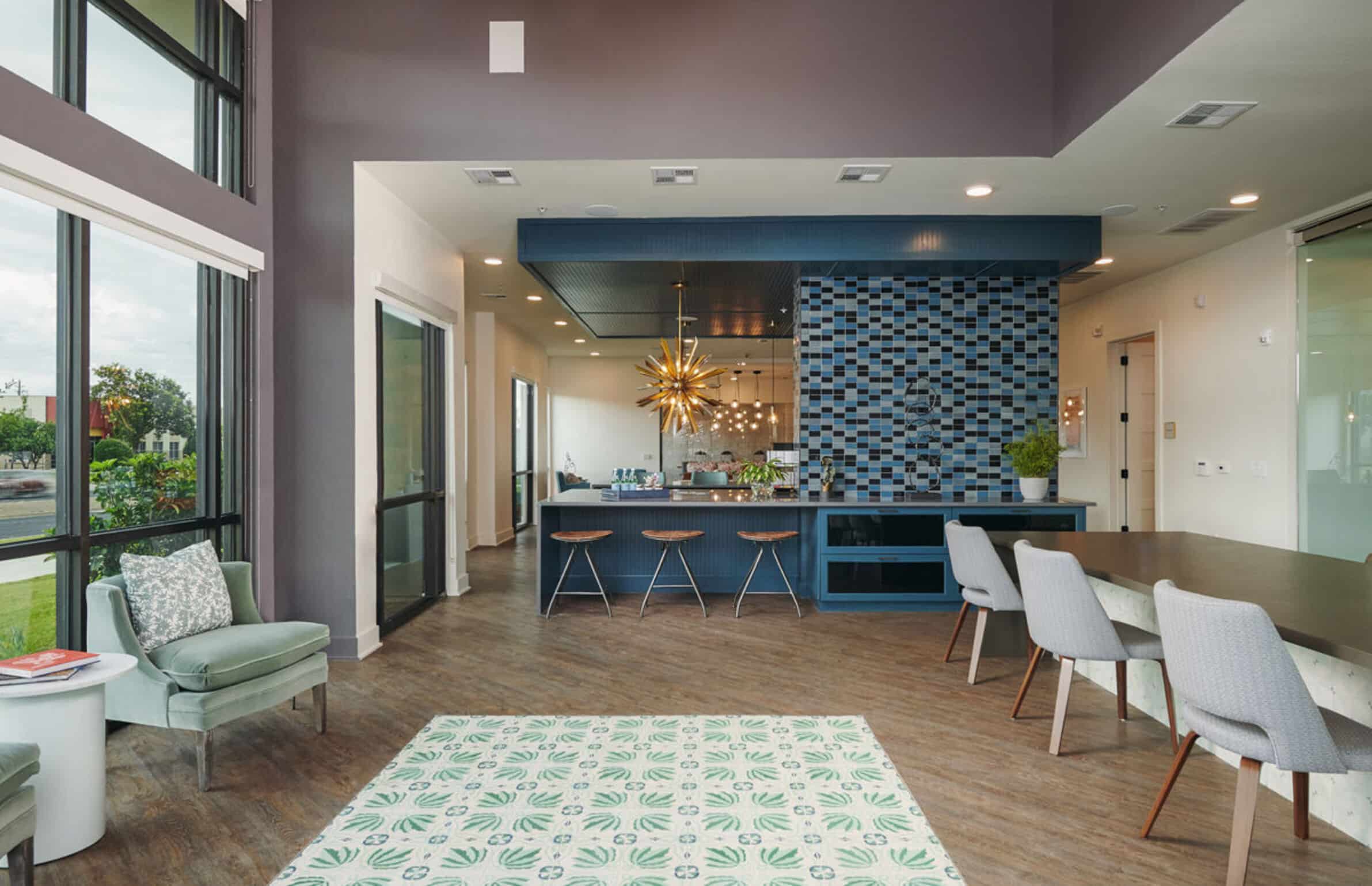 Modern lounge area in The Copeland with bar seating, patterned blue tile wall, and large windows letting in natural light.