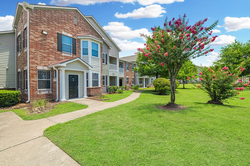 The Bryx at Kingwood with green lawns, trees, and a clear blue sky with white clouds.