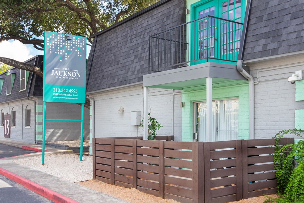 One of The Jackson townhome exteriors with a balcony and a fenced patio.