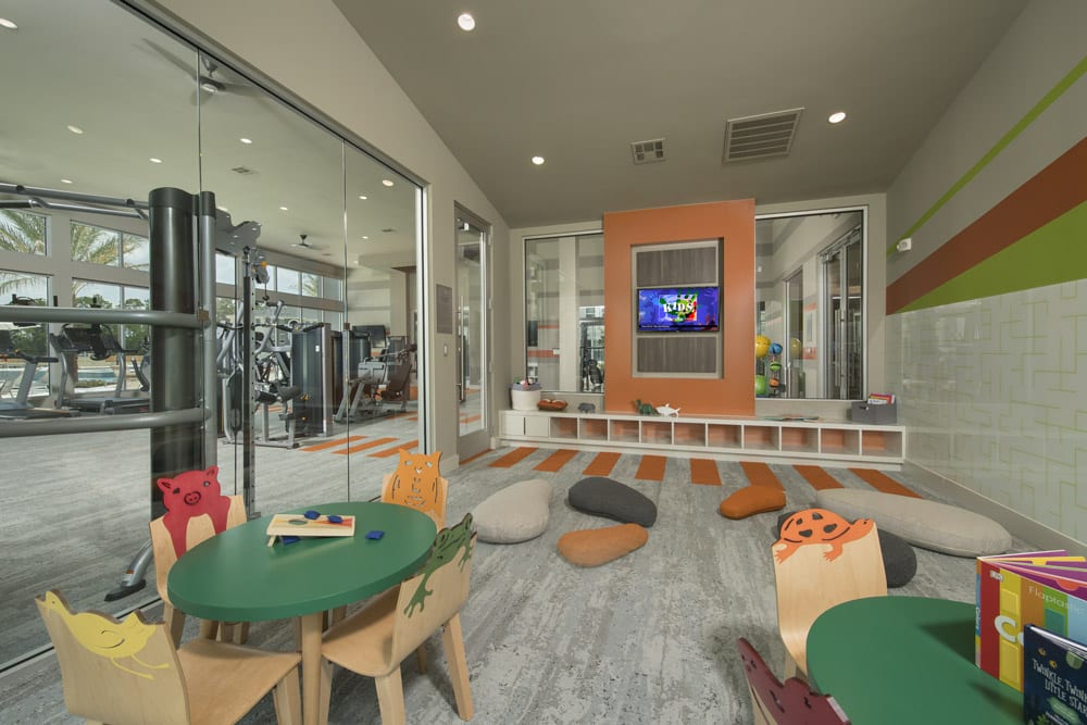 Children’s playroom at The Parkway on Westlake with colorful animal chairs, round tables, cushions, and a TV.