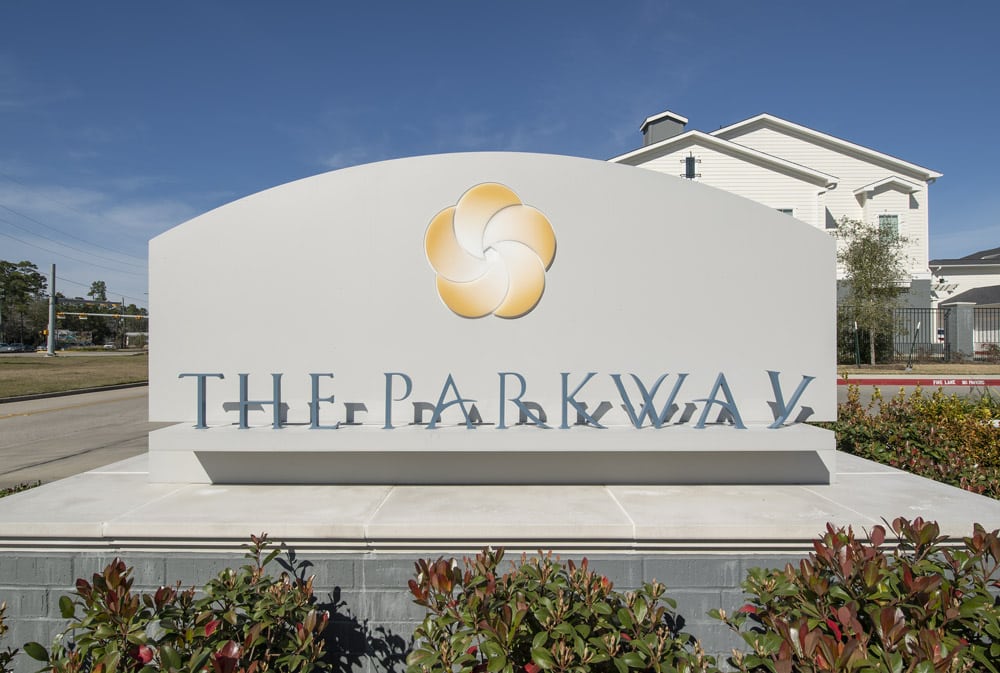 Entrance sign at The Parkway on Westlake in front of a building and blue sky.
