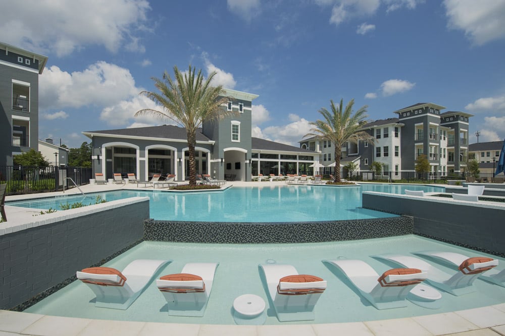 The Parkway on Westlake pool with palm trees and lounge chairs under a blue sky with clouds.