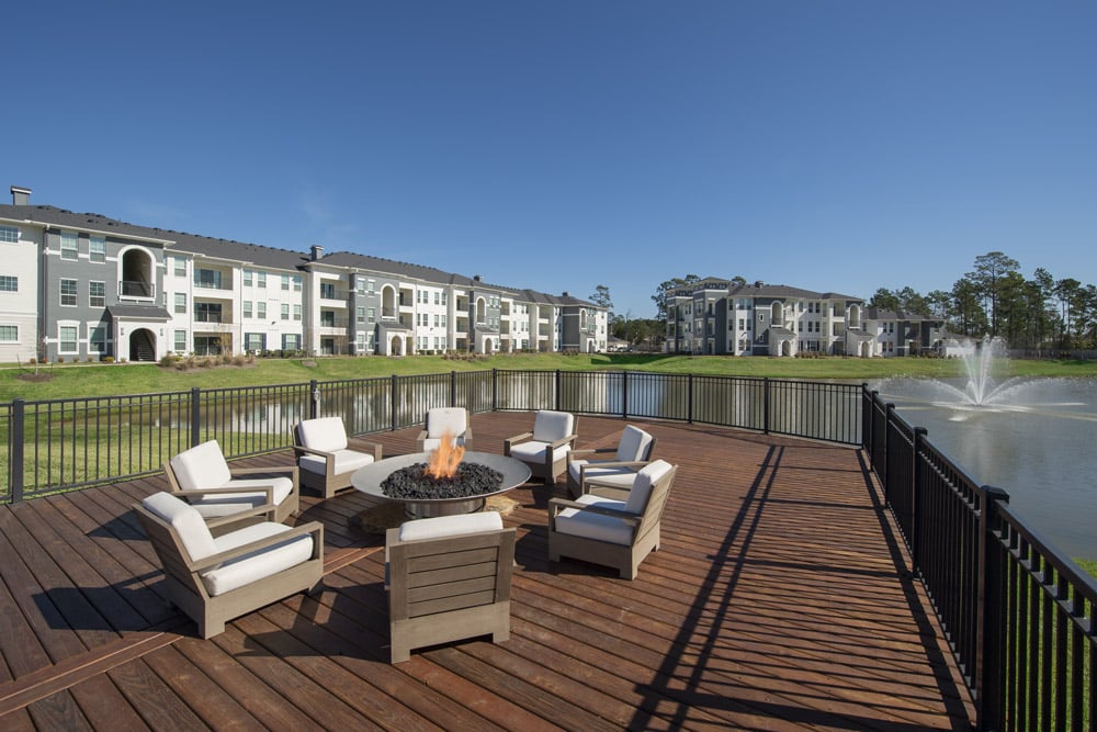 Outdoor patio at The Parkway on Westlake with chairs and a fire pit overlooking a pond and fountain.