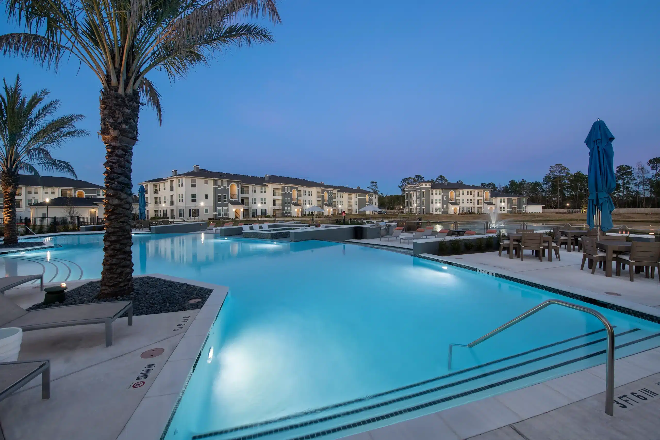 The Parkway on Westlake pool area at dusk with palm trees, lounge chairs, and outdoor seating.