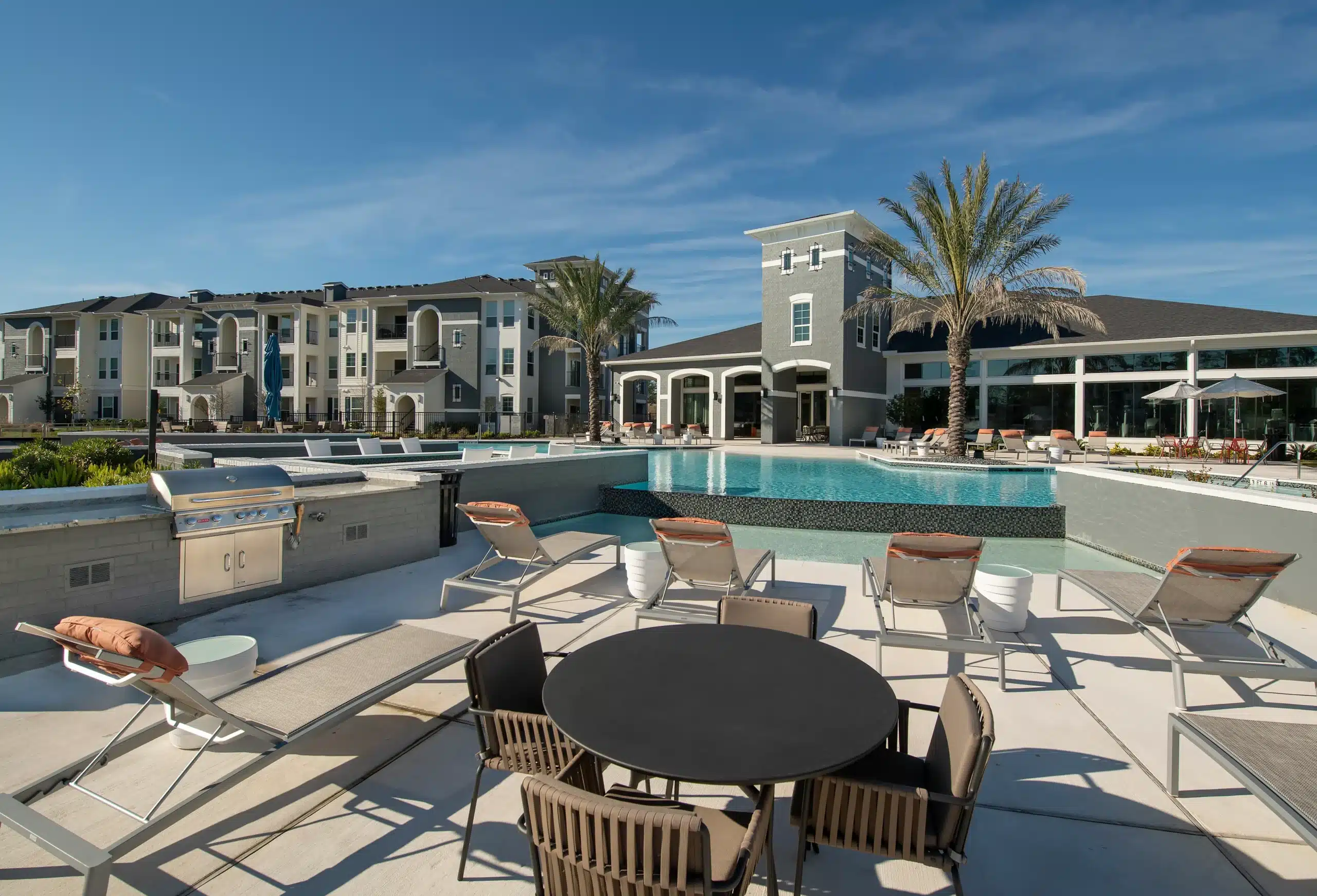 The Parkway on Westlake pool with lounge chairs, grill area, palm trees, and a clear blue sky.