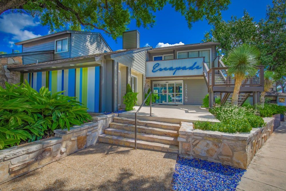 The Escapade entrance with blue accents, stairs, and lush plants.